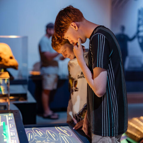 Two teenage boys looking amazed while learning about Sea Monsters at the exhibition.